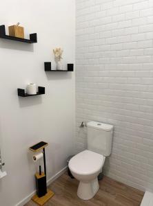 a bathroom with a toilet and a white brick wall at Little Wild - Centre Ville in Saverne