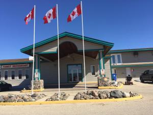 um edifício com três bandeiras canadianas à sua frente em Agassiz Park Lodge em McCreary