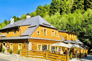 a large wooden building with a black roof at pension U Jiřího in Ludvíkov