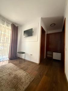 a living room with a table and a television on a wall at Casa TeoDora Caciulata in Căciulata