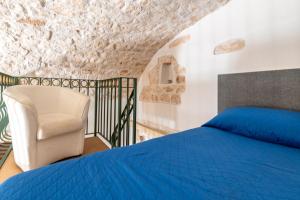 a bedroom with a blue bed and a chair at White Stone Flats & Studios in Ostuni
