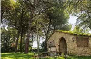 a small stone building with trees in a field at La locanda delle pulci in Colombella
