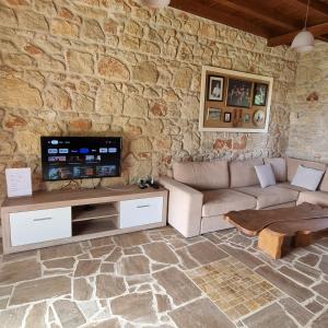 a living room with a couch and a tv in a stone wall at Fruit Garden Villas in Kriopigi