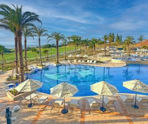 a large swimming pool with chairs and palm trees at PGM Hotel Resort Okinawa in Onna