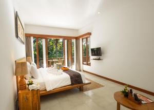 a bedroom with a bed and a large window at Purana Boutique Resort in Ubud