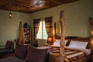 a bedroom with a bed and a couch and a window at Voyager's Center in Kikorongo