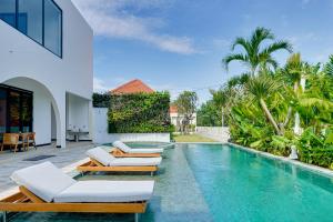 a swimming pool with lounge chairs next to a house at Bhatara Villa Sanur in Sanur