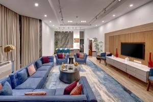 a living room with blue couches and a tv at Pearl Continental Hotel, Bhurban in Bhurban
