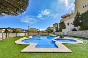 a swimming pool in a yard with green grass at Bungalow Montesol con Vistas al Mar y Montaña in Calpe