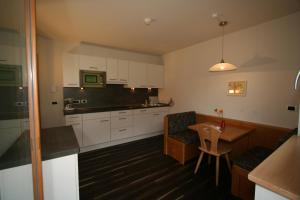 a kitchen with white cabinets and a wooden table at Residence Rosengarten - Alpenglühen zum Anfassen, inklusive Guestpass in Tires +12 photos