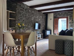 a dining room with a table and chairs and a stone wall at Apartament Cal Barracaire in Vilallonga de Ter