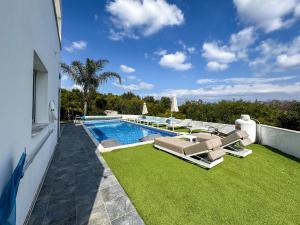 a swimming pool with chaise lounges next to a house at Akefalou Bay Villa in Protaras