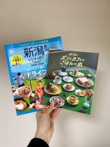 Eine Person hält ein Kochbuch hoch. in der Unterkunft Hanazono501 in Niigata