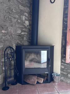 a fireplace with a tv in front of a stone wall at Apartament Cal Barracaire in Vilallonga de Ter