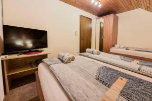 a room with two beds and a flat screen tv at Apartma Horvat in Bohinj