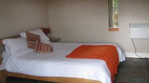 um quarto com uma cama branca e um cobertor laranja em Turfcutters Arms em Boldre