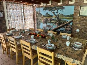 a dining room table with chairs and a painting on the wall at Weltevrede Lodge - Self Catering Houses in Marloth Park