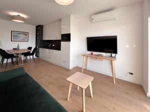 a living room with a couch and a table with a television at Posesja Kapitańska Apartament 18B 17 przy plaży in Grzybowo