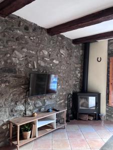 a living room with a tv on a stone wall at Apartament Cal Barracaire in Vilallonga de Ter