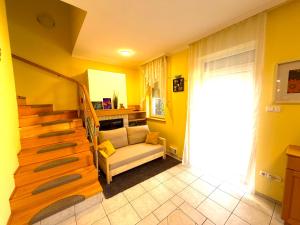 a yellow living room with a couch and stairs at Aurora Premium Home in Győr