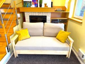 a couch with two yellow pillows sitting in front of a fireplace at Aurora Premium Home in Győr +25 photos