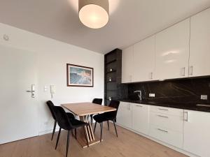 a kitchen with white cabinets and a wooden table and chairs at Posesja Kapitańska Apartament 18B 17 przy plaży in Grzybowo