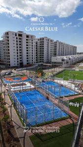 a tennis court with blue nets in front of a building at Gloria Apartments in Caesar Blue Resort,Gym, Swimming Pools, Sauna, Hammam, Kids' club available in Perivolia tou Trikomou +33 photos