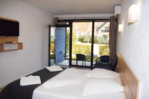 a bedroom with a white bed and a large window at Pensiunea Duet in Sărata-Monteoru