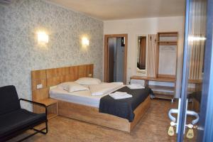 a bedroom with a bed and a chair in it at Pensiunea Duet in Sărata-Monteoru