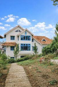 a white house with a pathway in front of it at Tomato Villa & Restaurant in Da Lat