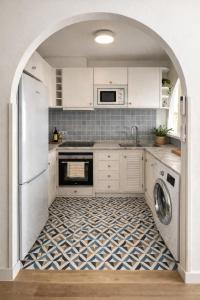 a kitchen with white cabinets and a patterned floor at Apartamento Ada a 2 minutos de la playa y con piscina! in Arenal d'en Castell