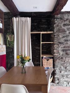 a dining room with a wooden table and a stone wall at Apartament Cal Barracaire in Vilallonga de Ter