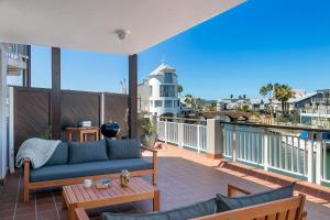 a patio with a couch and tables on a balcony at Knysna Waterfront, Stunning Views in Knysna