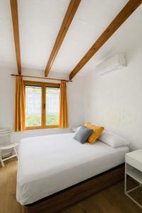 a bedroom with a large white bed and a window at Apartamento Ada a 2 minutos de la playa y con piscina! in Arenal d'en Castell +18 photos
