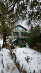 a large house in the snow with trees at Vibe Hostel Naddi - Near Dal Lake in Dharamshala