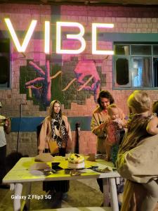 a group of people standing around a table with a cake at Vibe Hostel Naddi - Near Dal Lake in Dharamshala