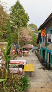 a patio with tables and chairs and a building at Vibe Hostel Naddi - Near Dal Lake in Dharamshala