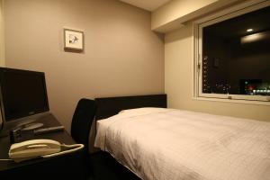 a room with a bed and a phone and a window at Hotel Crown Hills Kimitsu in Kimitsu