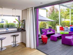 a patio with purple chairs and a table and chairs at ibis Styles Rennes St. Gregoire in Saint-Grégoire