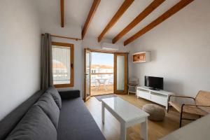 a living room with a couch and a table at Apartamento Ada a 2 minutos de la playa y con piscina! in Arenal d'en Castell