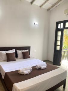 a bedroom with a large bed with two towels on it at AYUBELLO hostel & suites in Ahungalla