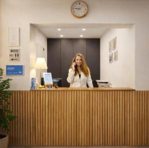 Eine Frau telefoniert in einem Büro mit einem Handy. in der Unterkunft Airport Messe Hotel in Düsseldorf