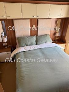 a bedroom with a large bed with blue sheets and pillows at CJ Coastal Getaway #1 in Abergele