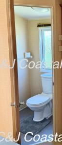 a bathroom with a toilet and a window at CJ Coastal Getaway #1 in Abergele +14 photos