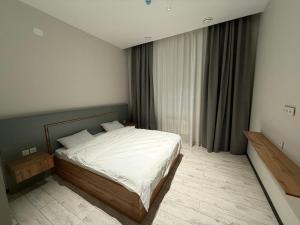 a bedroom with a bed with white sheets and a window at Гостиница Ислам in Khromtaū