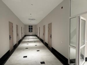 an empty hallway with many doors and a tile floor at Гостиница Ислам in Khromtaū