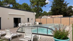a deck with chairs and a glass pool at Villa turquoise - piscine privée, terrasse bois in Saint-Jean-de-Monts