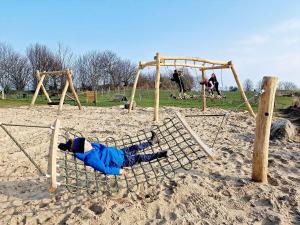 a person laying on a swing set in the sand at Ostseeferienpark Walkyrien in Schashagen +33 photos