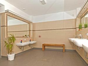a bathroom with three sinks and a mirror and a bench at Ostseeferienpark Walkyrien in Schashagen