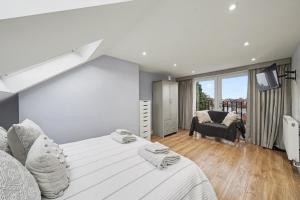 a white bedroom with a large bed and a chair at Finest Retreats - Twickers Townhouse in Whitton